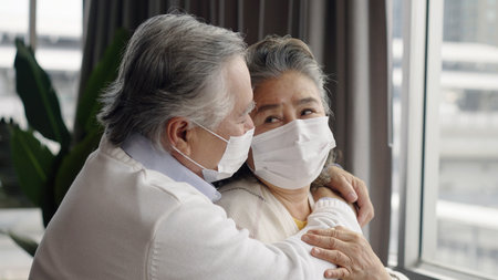 Two elderly Asian couples wearing masks hug and encourage each other.の写真素材