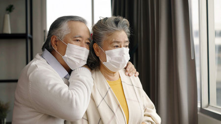 Two elderly Asian couples wearing masks hug and encourage each other.の写真素材