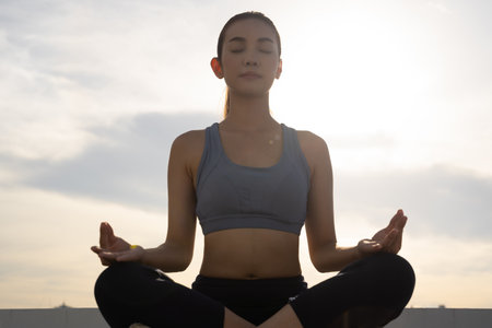 Young Asian slim fit woman meditating outdoors in the cityの写真素材