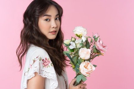 Young Asian woman holding a bouquet on hand isolated pink color backgroundの写真素材