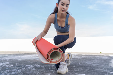 Young Asian woman picking up yoga mat after exercising.outdoor exercise fitness conceptの写真素材
