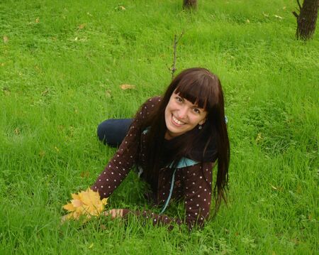Girl is laying on green grass in autumnの写真素材