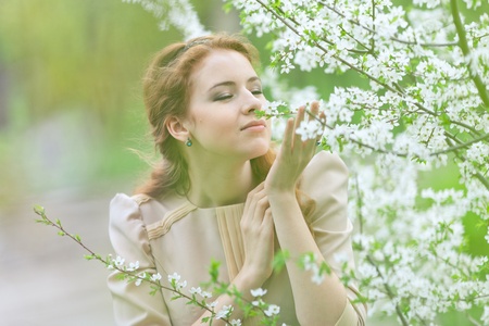 beautiful girl with red hair in spring cherry gardenの写真素材