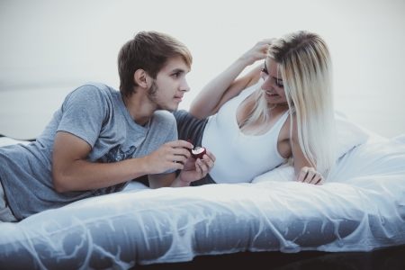 Young man romantically proposing to girlfriend and offering engagement ring