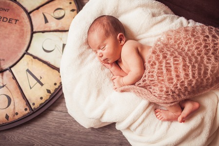 Sweet newborn baby. Big watch on baclground. Concept about timeの写真素材