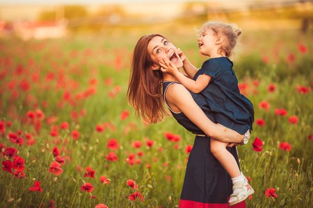 Young beautiful mother with daughter in the poppy meadowの写真素材
