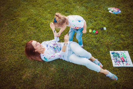 Mother and little daughter paint together outdoors