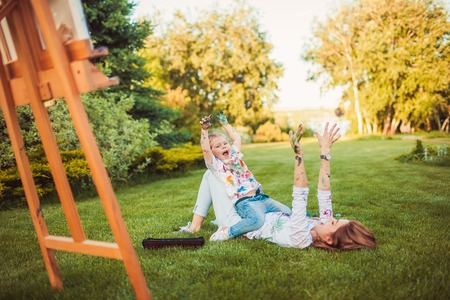 Mother and little daughter paint together outdoors