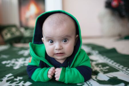 Portrait of cute little baby on christmas blanket in green suitの写真素材