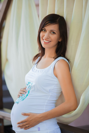 Smiling pregnant woman holding her hands on bellyの写真素材