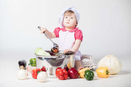 Little chef girl preparing healthy food on white backgroundの写真素材