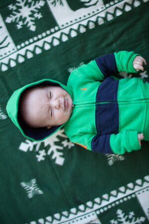 Portrait of cute little baby on christmas blanket in green suitの写真素材