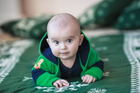 Portrait of cute little baby on christmas blanket in green suitの写真素材