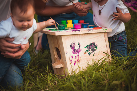 Happy family with nesting box and colorful paints in green summer forestの写真素材