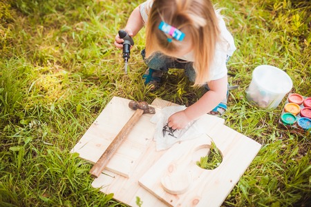 Little girl making Wooden birdhouse in summer green parkの写真素材