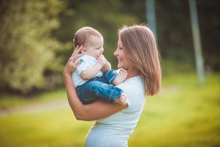 Happy mother with baby in summer green parkの写真素材