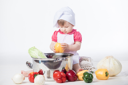 Little chef girl preparing healthy food on white backgroundの写真素材