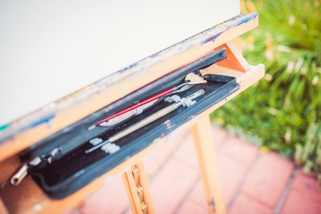 Easel with sheet of paper and art suppliesの写真素材