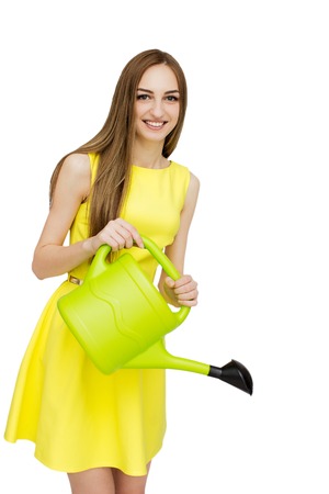 Portrait of beautiful woman in yellow dress with watering canの写真素材