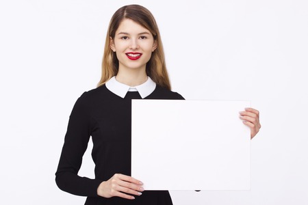 Advertising. Woman in black dress. Smiling woman showing blank card or paper on white background.の写真素材