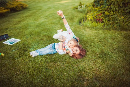 Mother and little daughter paint together outdoorsの写真素材