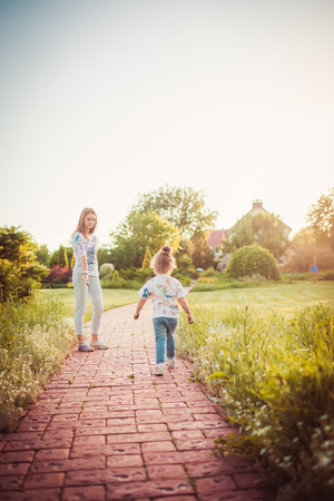Mother and little daughter walking together in a parkの写真素材