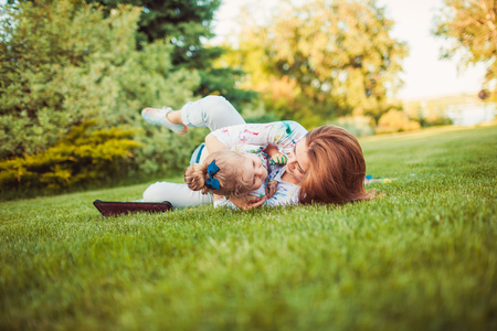 Mother and little daughter playing together in a parkの写真素材