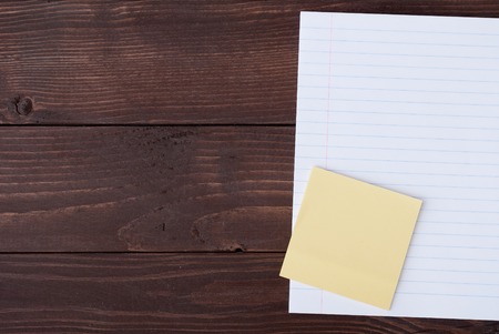 School stationery with copyspace on wooden board. Memo stick and exercise-book on wooden tableの写真素材