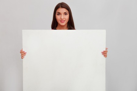 Woman showing copy space for product or text on open hand palm, smiling joyful and happy. Caucasian female girl presenting something isolated on white background. Copyspase for product or sign textの写真素材