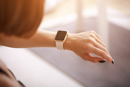 using her smartwatch at home in the living roomの写真素材