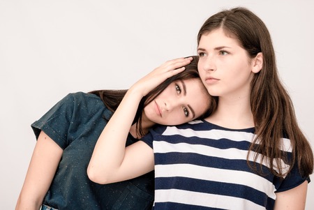 Troubled young girl being consoled by her friend. Friendship help support and difficult times concept.の写真素材