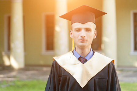 Graduate students wearing graduation hat and gown, outdoorsの写真素材