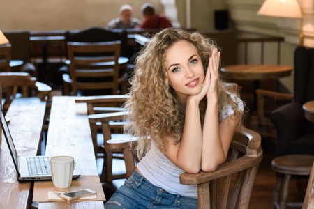 Portait of happy woman sitting at cafe with laptop. Looking at cameraの写真素材