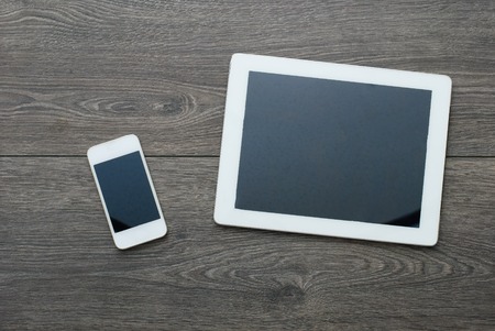 Tablet computer on pink wooden boards. White screen. Top view.の写真素材