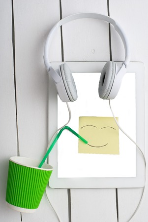 White tablet computer and the white headphones on wood boardの写真素材
