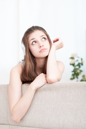 Happy girl on the couch at home in the living roomの写真素材