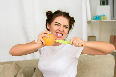 Portrait of young and healthy woman with orange in her living roomの写真素材
