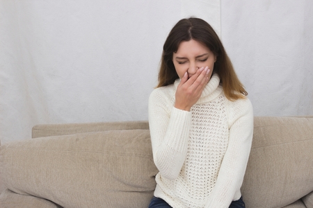 Portrait of young woman sitting on couch in her living room