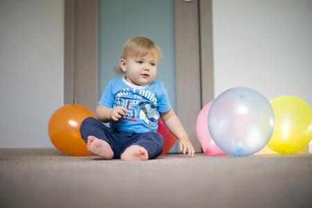 baby playing with balloons at home