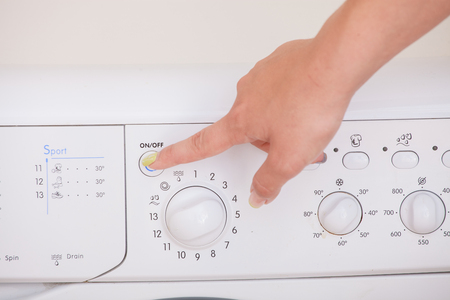 Close up of girls hand adjusting washing machine.の写真素材