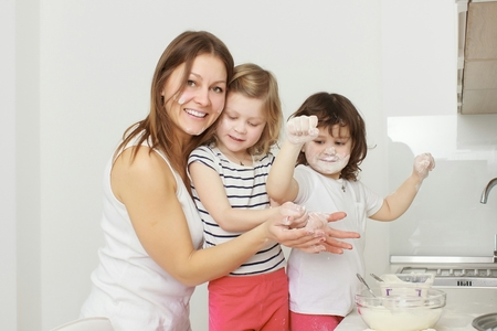 Mother with her 5 years old kids cooking holiday pie in the kitchenの写真素材