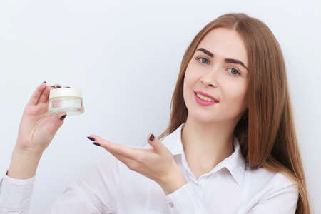 Young beautiful smiling woman with cosmetics bottle isolated on white backgroundの写真素材