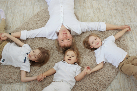 Top view of young father with three cute little sons lying on floorの写真素材