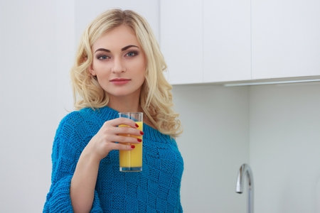 Beautiful young woman holding glass of orange juiceの写真素材