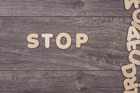 Word Stop made with wooden letters next to a pile of other letters over the wooden board surface compositionの写真素材