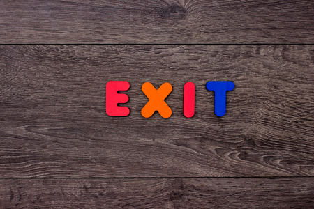 Word Exit from wooden letters on dark wooden background