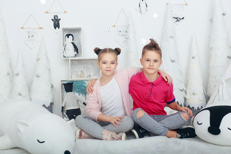 beautiful boy and girl, brother and sister, sitting on floor in xmas decorated room and smilingの写真素材