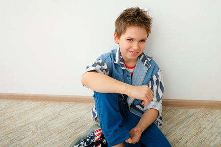 young attractive teenager boy sitting on floor and smilingの写真素材