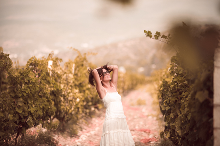 Smiling woman in white dress standing in vineyardの写真素材