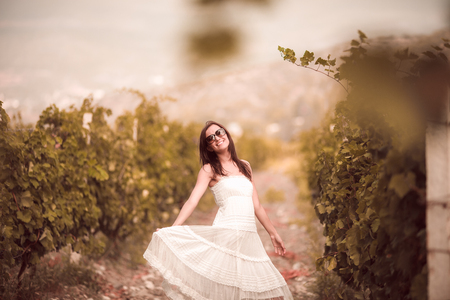 Smiling woman in white dress standing in vineyardの写真素材